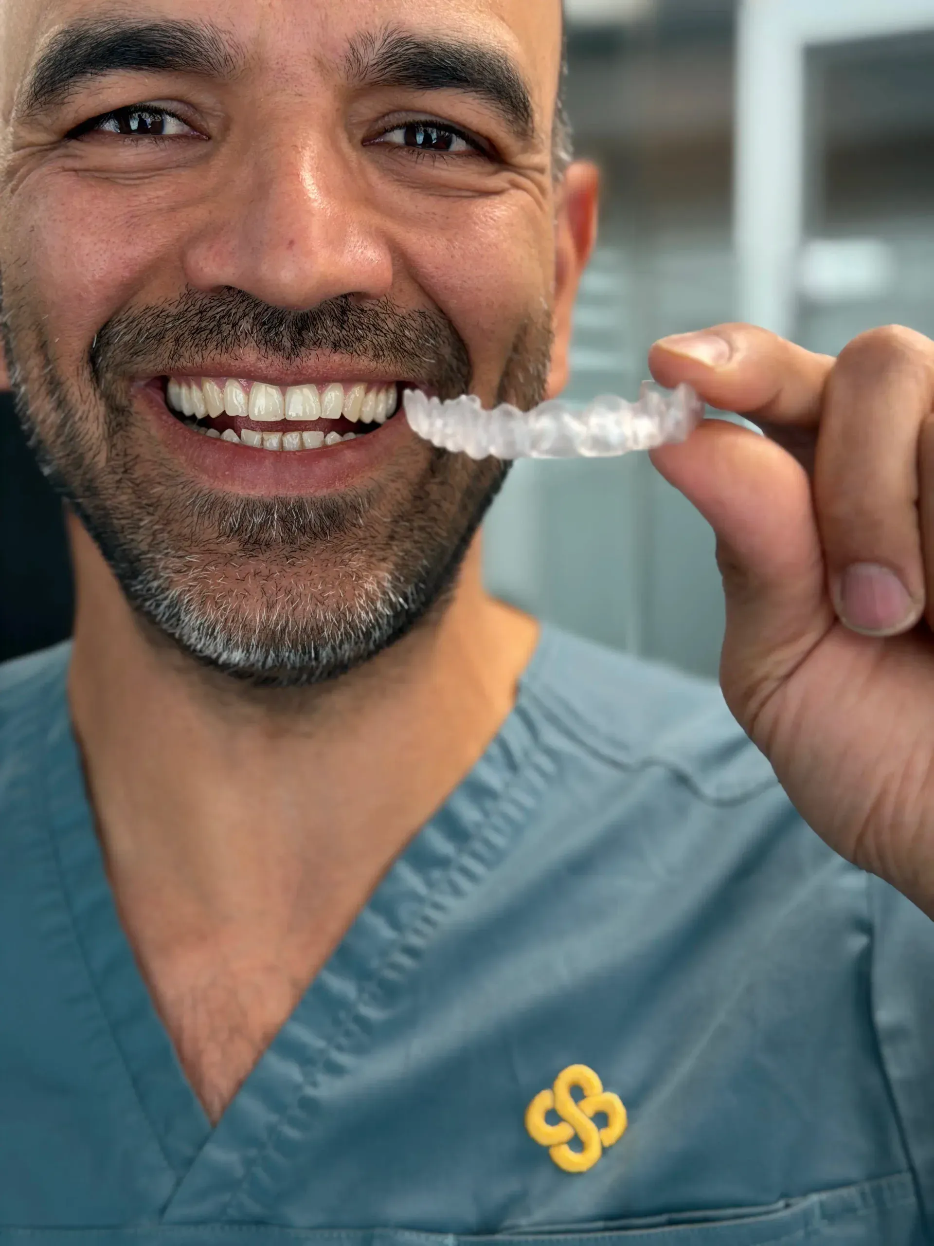 Tannlege ved Oslo Tannlegesenter holder opp en gjennomsiktig Invisalign-skinne