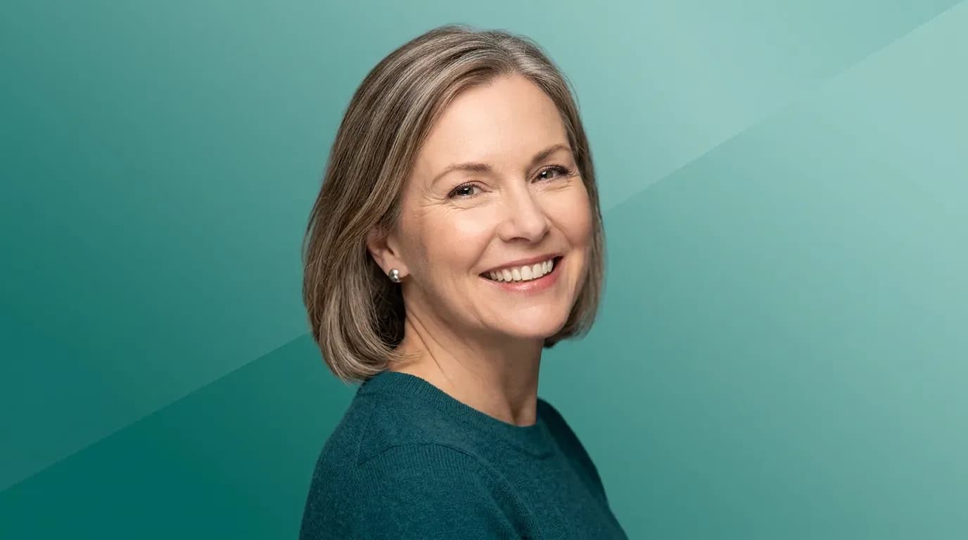 Nærbilde av person i 40-50-årene med varmt smil og naturlige tenner mot teal gradientbakgrunn